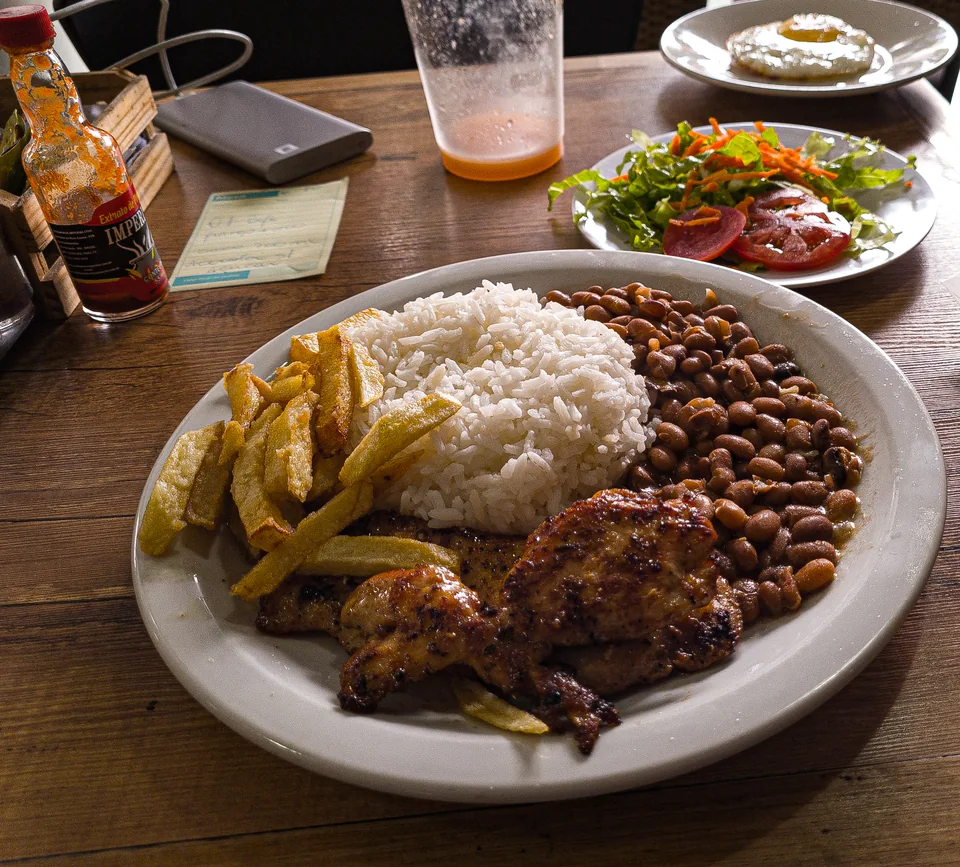 Prato de arroz, feijão e frango grelhado sobre uma mesa